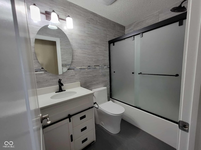 11070 Long Lake Ln, Fishers, IN 46037 - bathroom featuring tile walls, a textured ceiling, vanity, toilet, and combined bath / shower with glass door