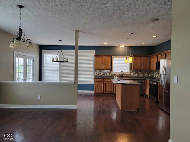 11070 Long Lake Ln, Fishers, IN 46037 - kitchen with appliances with stainless steel finishes, a chandelier, dark countertops, brown cabinets, and backsplash