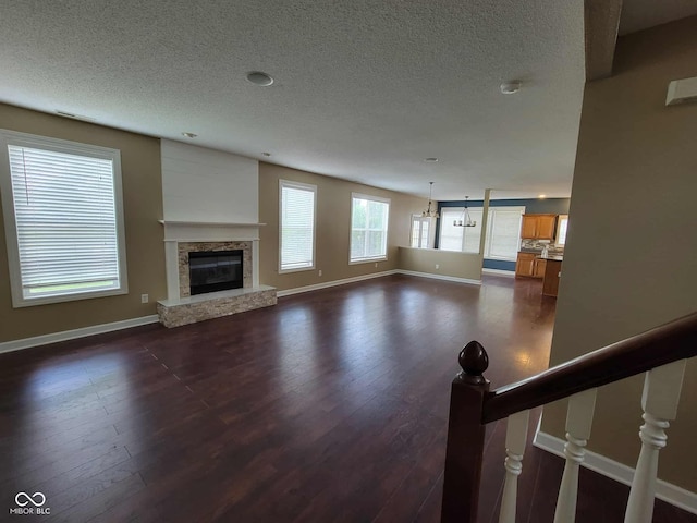 11070 Long Lake Ln, Fishers, IN 46037 - unfurnished living room with a textured ceiling, dark wood finished floors, baseboards, and a stone fireplace