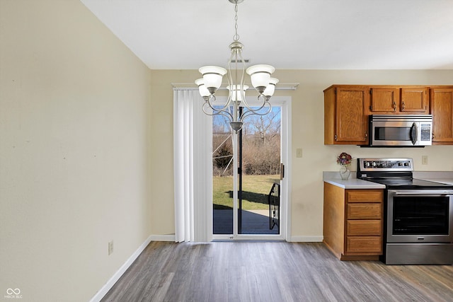 1024 Rotherham Ln, Beech Grove, IN 46107 - kitchen with stainless steel appliances, a chandelier, baseboards, brown cabinetry, and light wood-style floors