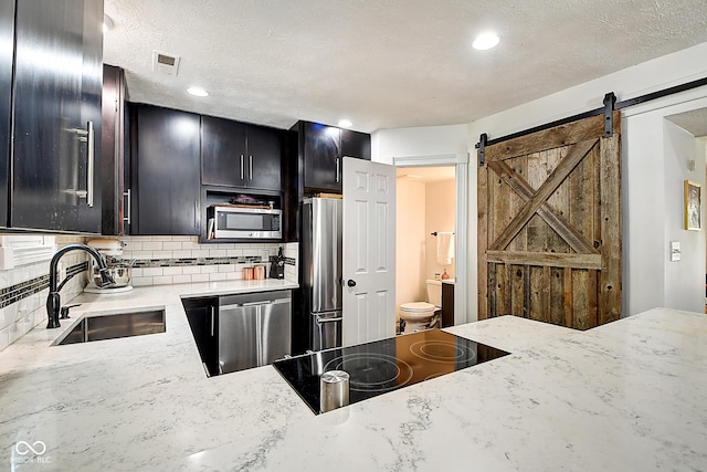 1548 N Park Ave, Indianapolis, IN 46202 - kitchen featuring stainless steel appliances, a sink, dark cabinets, decorative backsplash, and a textured ceiling