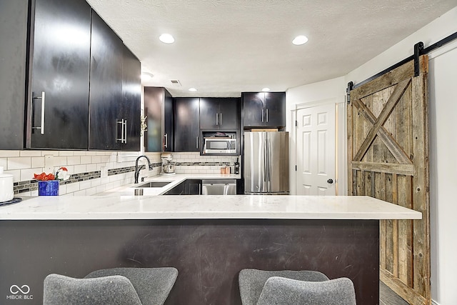 1548 N Park Ave, Indianapolis, IN 46202 - kitchen with stainless steel appliances, a sink, tasteful backsplash, dark cabinets, and a barn door