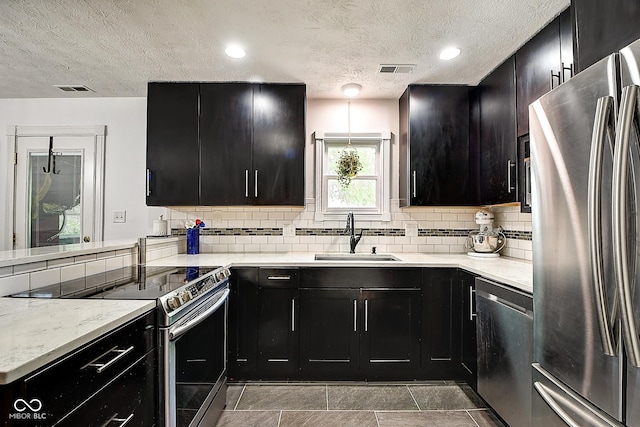 1548 N Park Ave, Indianapolis, IN 46202 - kitchen featuring stainless steel appliances, a sink, dark cabinetry, a textured ceiling, and backsplash