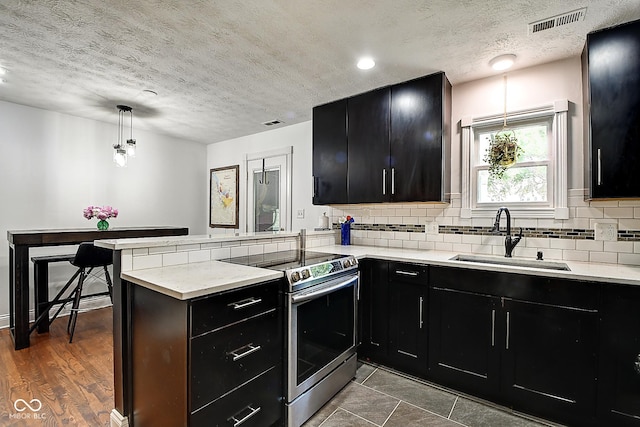 1548 N Park Ave, Indianapolis, IN 46202 - kitchen featuring dark cabinetry, stainless steel range with electric stovetop, a sink, a peninsula, and tasteful backsplash