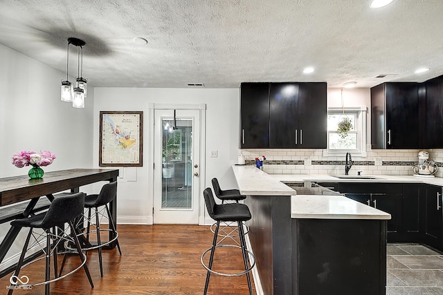1548 N Park Ave, Indianapolis, IN 46202 - kitchen featuring dark cabinetry, a sink, light countertops, a peninsula, and a kitchen bar