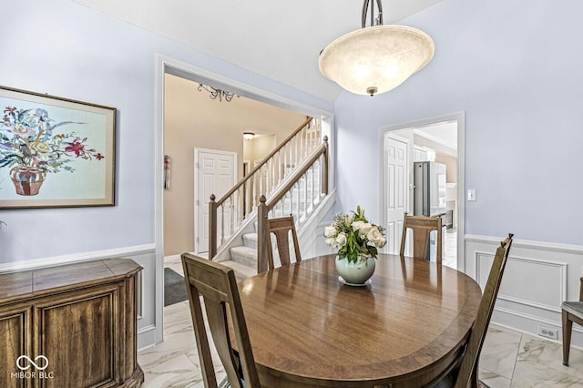 11244 Blackwalnut Pt, Indianapolis, IN 46236 - dining area featuring light marble finish floors, stairs, a wainscoted wall, and a decorative wall