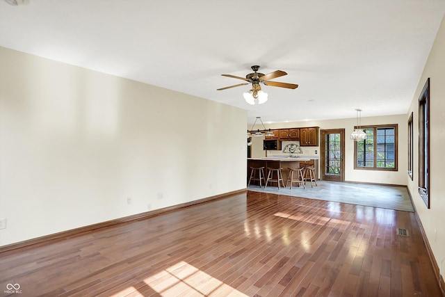 8619 Wrangler Ct, Indianapolis, IN 46217 - unfurnished living room featuring wood finished floors, baseboards, ceiling fan, and a chandelier