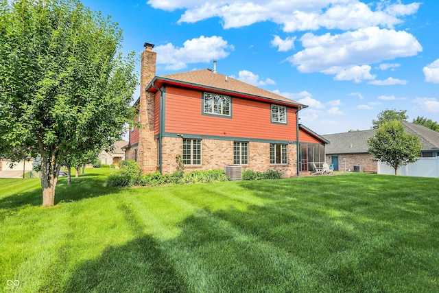 8619 Wrangler Ct, Indianapolis, IN 46217 - rear view of house featuring a chimney, a yard, cooling unit, brick siding, and a sunroom