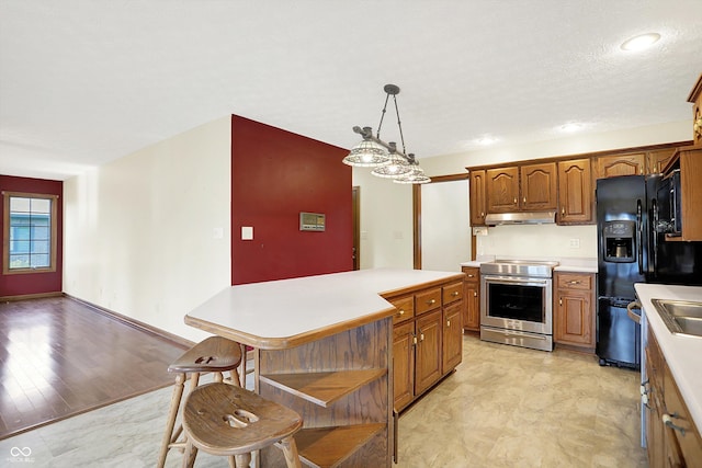 8619 Wrangler Ct, Indianapolis, IN 46217 - kitchen with electric range, under cabinet range hood, light countertops, and brown cabinetry