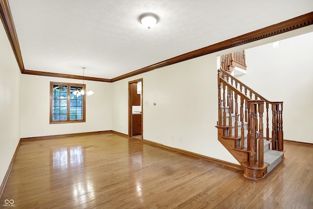 8619 Wrangler Ct, Indianapolis, IN 46217 - empty room with wood finished floors, ornamental molding, baseboards, a chandelier, and stairs