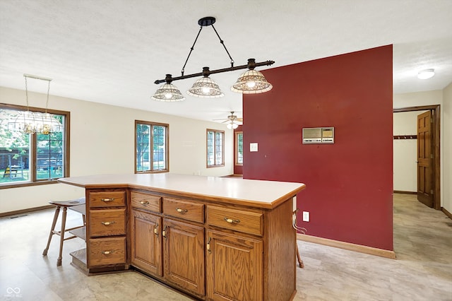 8619 Wrangler Ct, Indianapolis, IN 46217 - kitchen with baseboards, brown cabinetry, light countertops, a breakfast bar, and pendant lighting