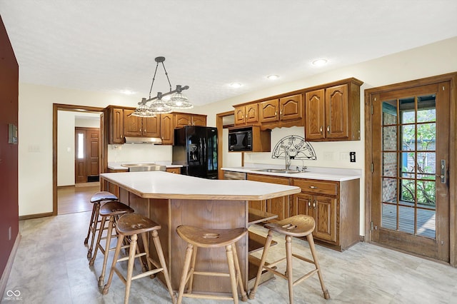 8619 Wrangler Ct, Indianapolis, IN 46217 - kitchen featuring black appliances, a sink, a breakfast bar area, light countertops, and recessed lighting