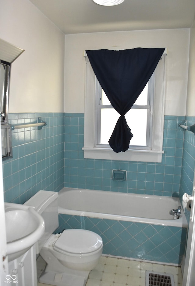 1641 Winton Ave, Speedway, IN 46224 - bathroom featuring tiled bath, toilet, tile walls, a wainscoted wall, and a sink