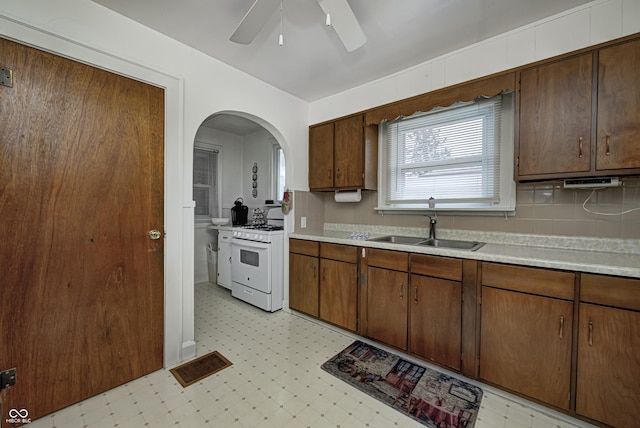 1641 Winton Ave, Speedway, IN 46224 - kitchen with white gas range oven, a sink, light floors, light countertops, and arched walkways