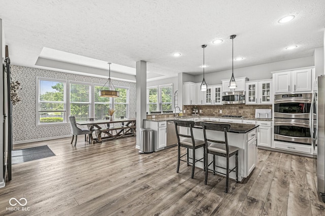 4642 Big Run Ct, Indianapolis, IN 46239 - kitchen with stainless steel appliances, wood finished floors, a textured ceiling, wallpapered walls, and white cabinets
