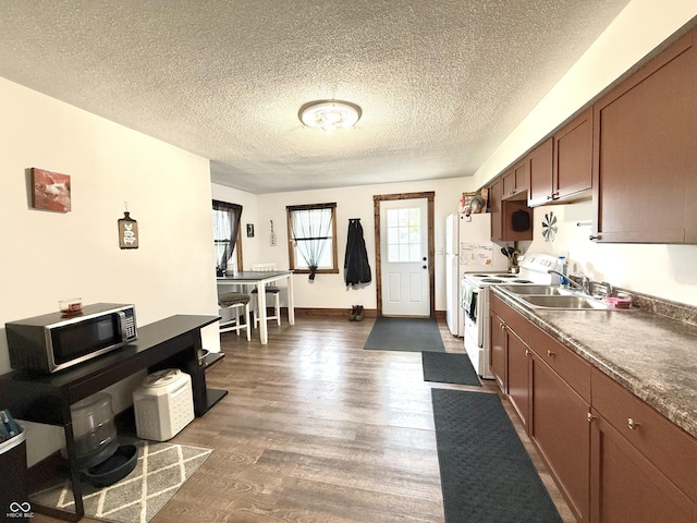 1126 S 20th St, New Castle, IN 47362 - kitchen featuring white appliances, dark wood finished floors, a sink, a textured ceiling, and brown cabinetry