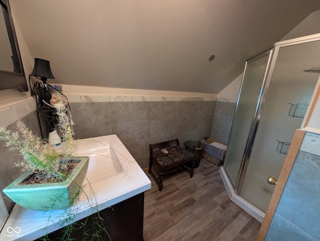 317 Washington St, Clay City, IN 47841 - bathroom featuring tile walls, a stall shower, vaulted ceiling, wood finished floors, and double vanity