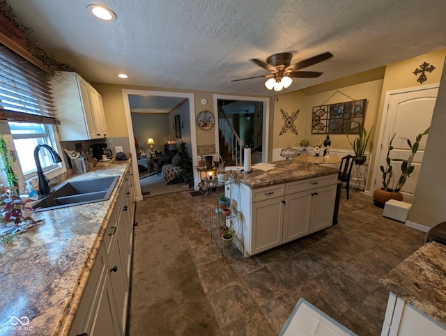 317 Washington St, Clay City, IN 47841 - kitchen featuring a sink, ceiling fan, a kitchen island, a textured ceiling, and white cabinetry