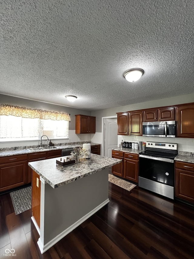 585 Fireside Dr, Greenwood, IN 46143 - kitchen featuring stainless steel appliances, a kitchen island, a textured ceiling, light countertops, and dark wood-style floors