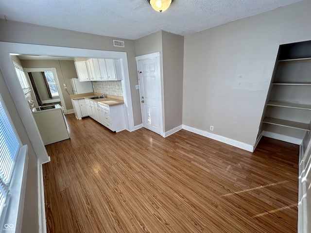 307 N Arlington Ave, Indianapolis, IN 46219 - kitchen featuring light countertops, white cabinets, baseboards, wood finished floors, and a textured ceiling