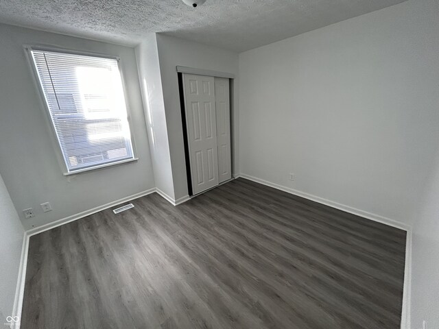 307 N Arlington Ave, Indianapolis, IN 46219 - unfurnished bedroom featuring a textured ceiling, dark wood-type flooring, a closet, and baseboards