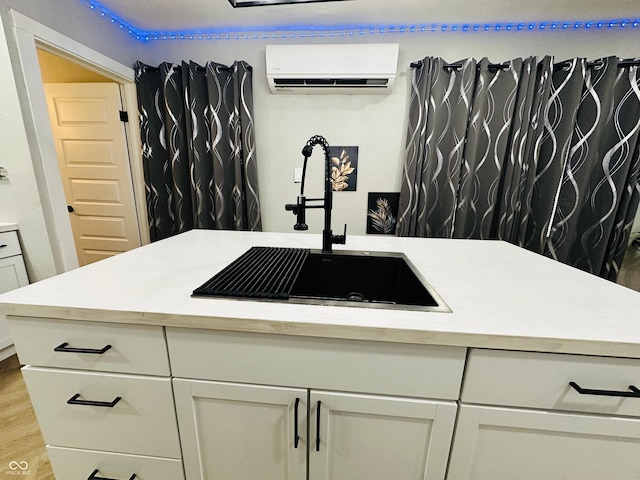 38 Hendricks Pl, Indianapolis, IN 46201 - kitchen featuring a wall mounted air conditioner, light countertops, white cabinets, and light wood finished floors