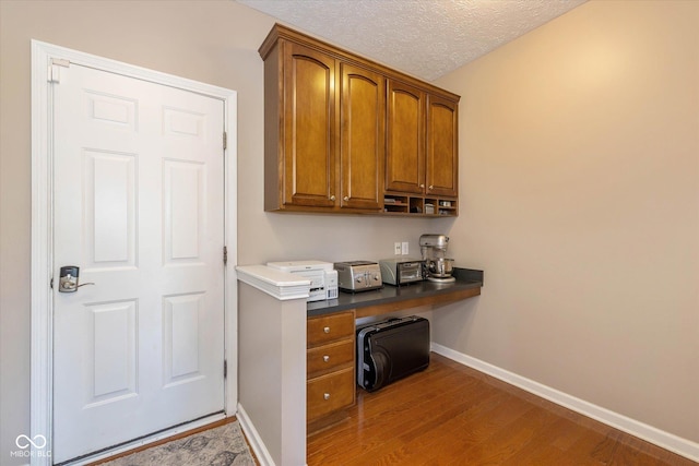 12772 Tram Ln, Carmel, IN 46032 - office featuring built in desk, wood finished floors, and a textured ceiling
