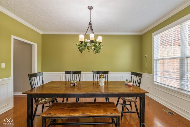 12772 Tram Ln, Carmel, IN 46032 - dining room featuring wood finished floors, ornamental molding, a wainscoted wall, a chandelier, and a decorative wall