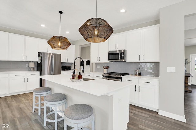 9716 Cimmaron Ave, Mccordsville, IN 46055 - kitchen featuring appliances with stainless steel finishes, light wood-style flooring, backsplash, a center island with sink, and a kitchen breakfast bar