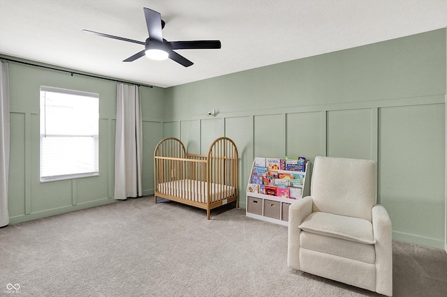 9716 Cimmaron Ave, Mccordsville, IN 46055 - carpeted bedroom with a decorative wall, a crib, ceiling fan, and wainscoting