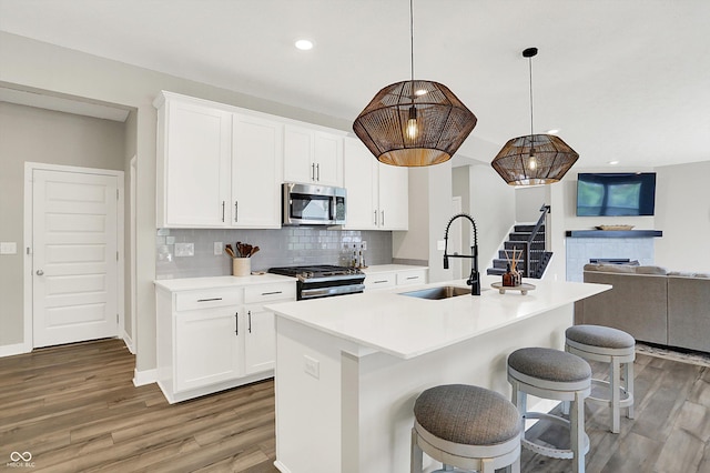 9716 Cimmaron Ave, Mccordsville, IN 46055 - kitchen with appliances with stainless steel finishes, a sink, light wood-style flooring, open floor plan, and decorative backsplash
