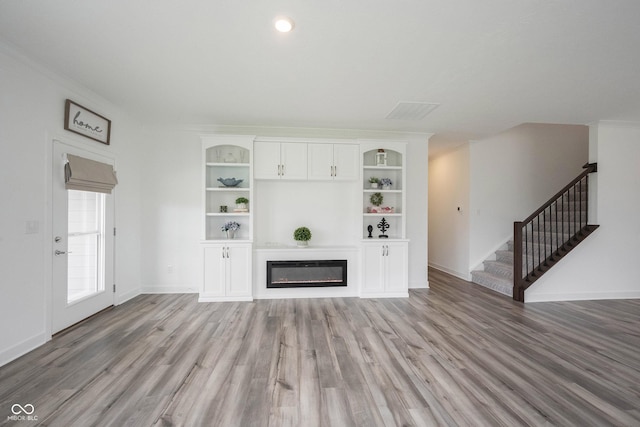 19800 Sutton Ter, Westfield, IN 46074 - unfurnished living room featuring light wood-type flooring, stairway, a glass covered fireplace, and baseboards