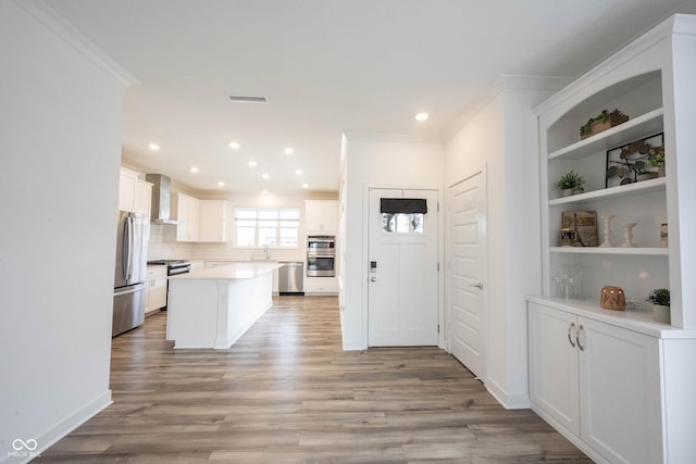 19800 Sutton Ter, Westfield, IN 46074 - kitchen with stainless steel appliances, wall chimney range hood, crown molding, a sink, and light wood-style floors