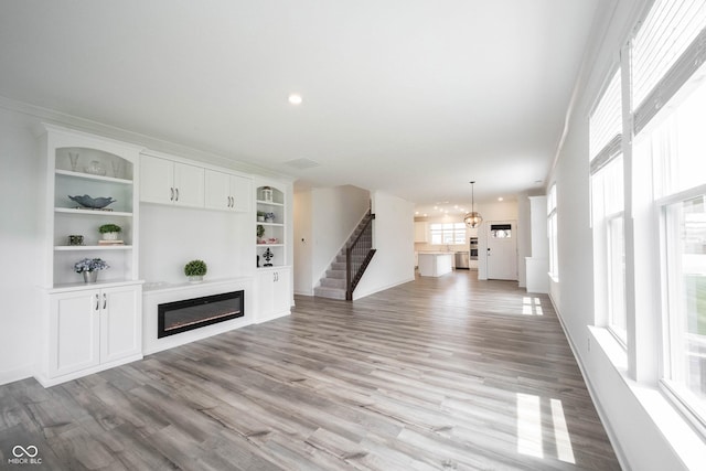 19800 Sutton Ter, Westfield, IN 46074 - unfurnished living room featuring light wood-type flooring, a glass covered fireplace, stairs, recessed lighting, and baseboards
