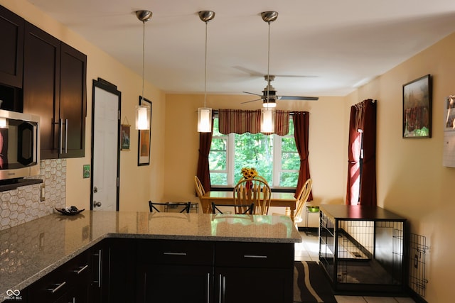 5654 Paradise Dr, Martinsville, IN 46151 - kitchen featuring a peninsula, decorative backsplash, stainless steel microwave, a ceiling fan, and light stone counters