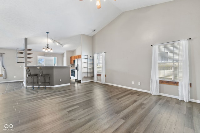 10693 Newgate Ln, Indianapolis, IN 46231 - unfurnished living room featuring a ceiling fan, dark wood-style floors, baseboards, high vaulted ceiling, and rail lighting