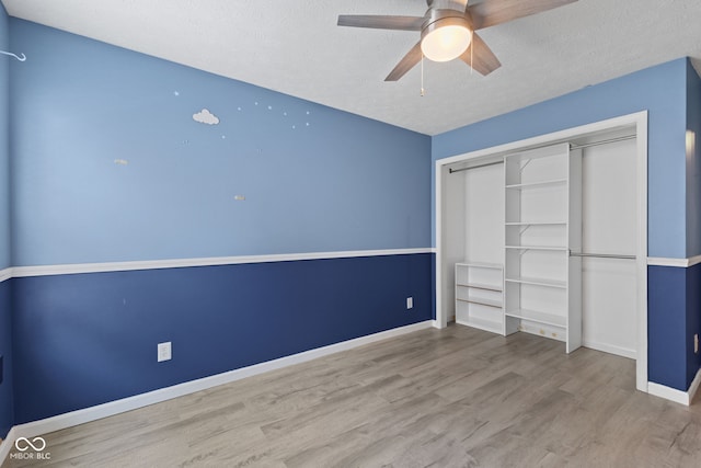10693 Newgate Ln, Indianapolis, IN 46231 - unfurnished bedroom with wood finished floors, baseboards, a closet, a textured ceiling, and a ceiling fan