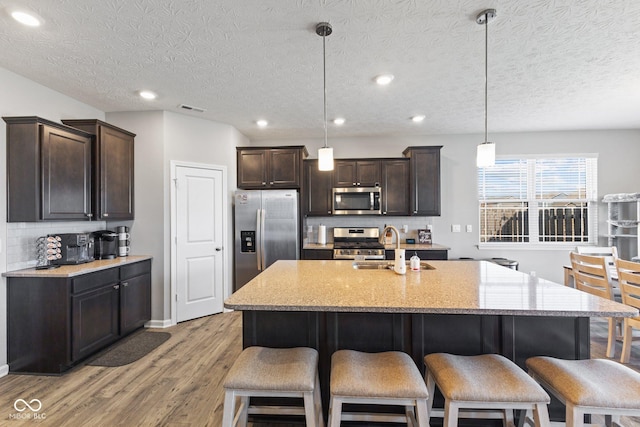 7834 Fairwood Blvd, Plainfield, IN 46168 - kitchen with appliances with stainless steel finishes, a sink, light wood-style flooring, decorative backsplash, and dark brown cabinetry