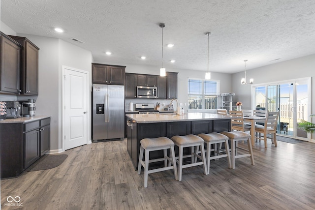 7834 Fairwood Blvd, Plainfield, IN 46168 - kitchen featuring appliances with stainless steel finishes, wood finished floors, dark brown cabinets, a sink, and a kitchen breakfast bar