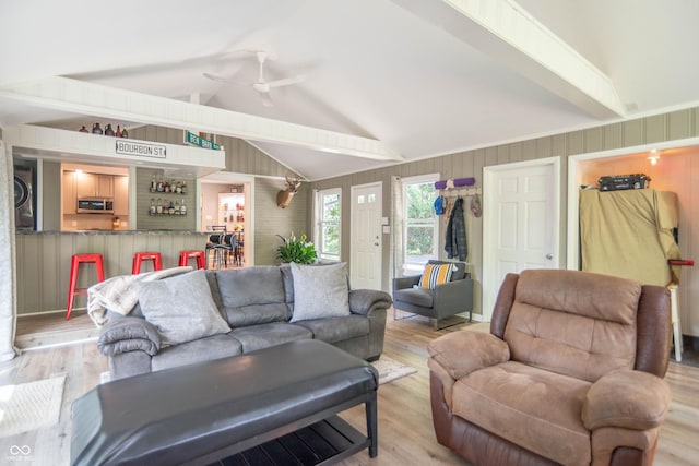 5315 Camden St, Indianapolis, IN 46227 - living room with light wood-style flooring, estacked washer and dryer, a bar, ceiling fan, and wood walls