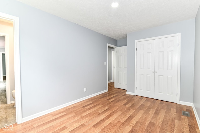 8445 Montery Rd, Indianapolis, IN 46226 - unfurnished bedroom with light wood-type flooring, baseboards, a closet, and a textured ceiling