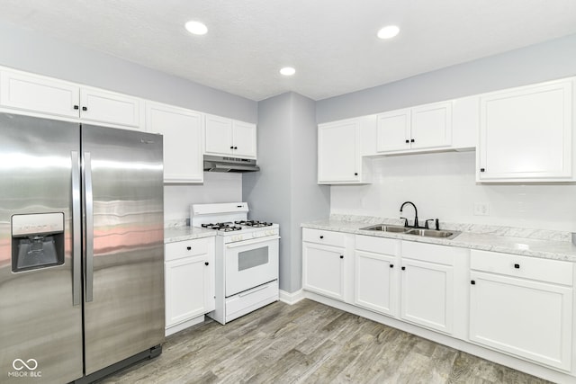 8445 Montery Rd, Indianapolis, IN 46226 - kitchen with stainless steel fridge, white gas range, under cabinet range hood, a sink, and white cabinets