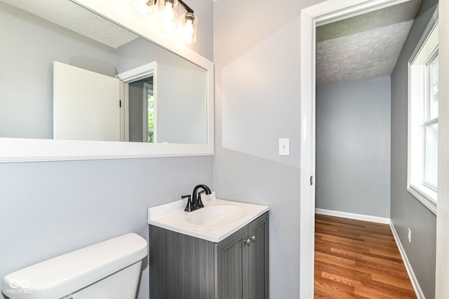 8445 Montery Rd, Indianapolis, IN 46226 - bathroom with vanity, wood finished floors, toilet, baseboards, and a textured ceiling