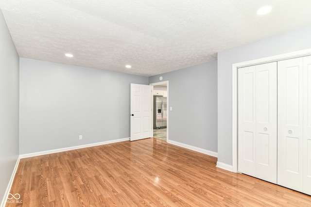 8445 Montery Rd, Indianapolis, IN 46226 - unfurnished bedroom featuring stainless steel fridge with ice dispenser, light wood-style flooring, baseboards, recessed lighting, and a textured ceiling