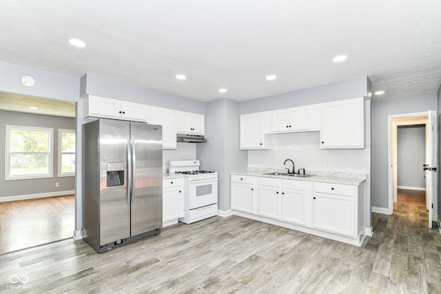 8445 Montery Rd, Indianapolis, IN 46226 - kitchen featuring white range with gas cooktop, stainless steel refrigerator with ice dispenser, under cabinet range hood, a sink, and baseboards