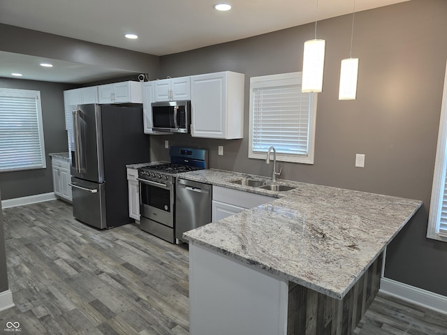 2035 S Pennsylvania St, Indianapolis, IN 46225 - kitchen with appliances with stainless steel finishes, a sink, baseboards, dark wood finished floors, and a peninsula