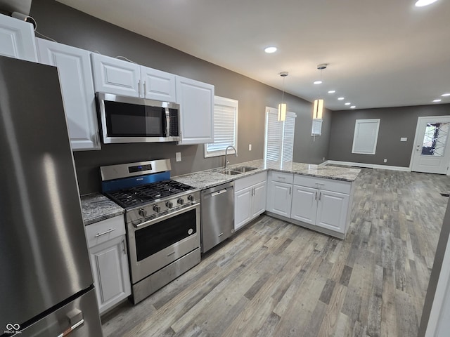 2035 S Pennsylvania St, Indianapolis, IN 46225 - kitchen featuring appliances with stainless steel finishes, a peninsula, white cabinetry, light wood-style floors, and recessed lighting