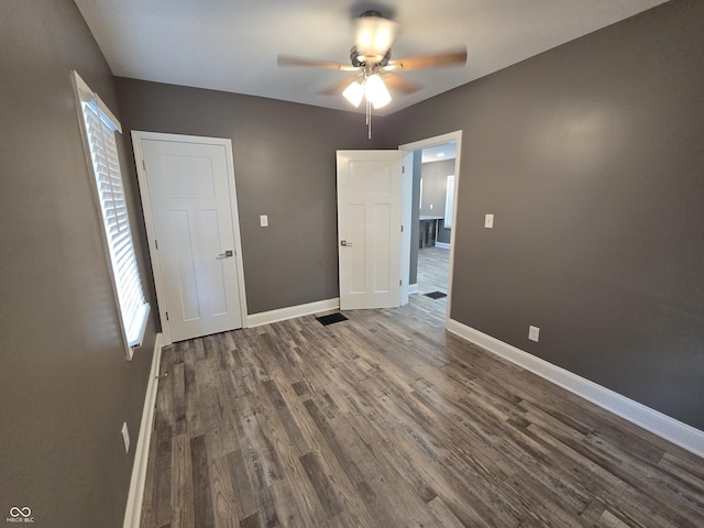 2035 S Pennsylvania St, Indianapolis, IN 46225 - unfurnished bedroom with baseboards, dark wood finished floors, and multiple windows