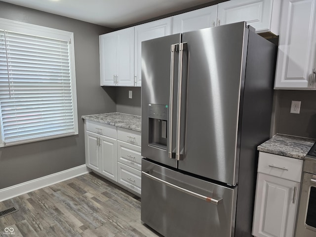 2035 S Pennsylvania St, Indianapolis, IN 46225 - kitchen with stainless steel refrigerator with ice dispenser, white cabinetry, light wood-style floors, baseboards, and light stone counters