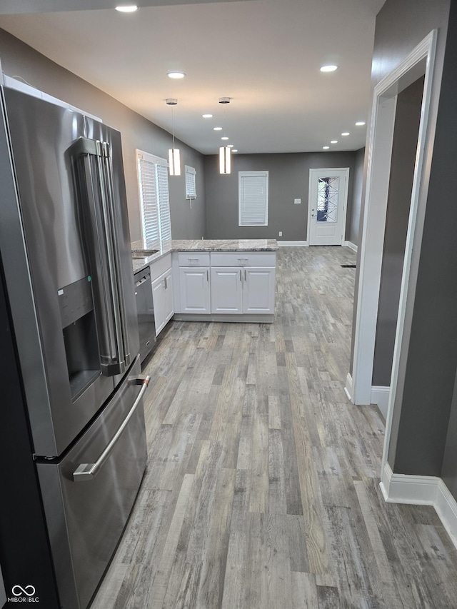 2035 S Pennsylvania St, Indianapolis, IN 46225 - kitchen featuring stainless steel appliances, white cabinetry, a peninsula, light wood-style flooring, and light stone counters